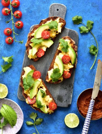 harissa, scrambled eggs and avocado toasts on a blue background