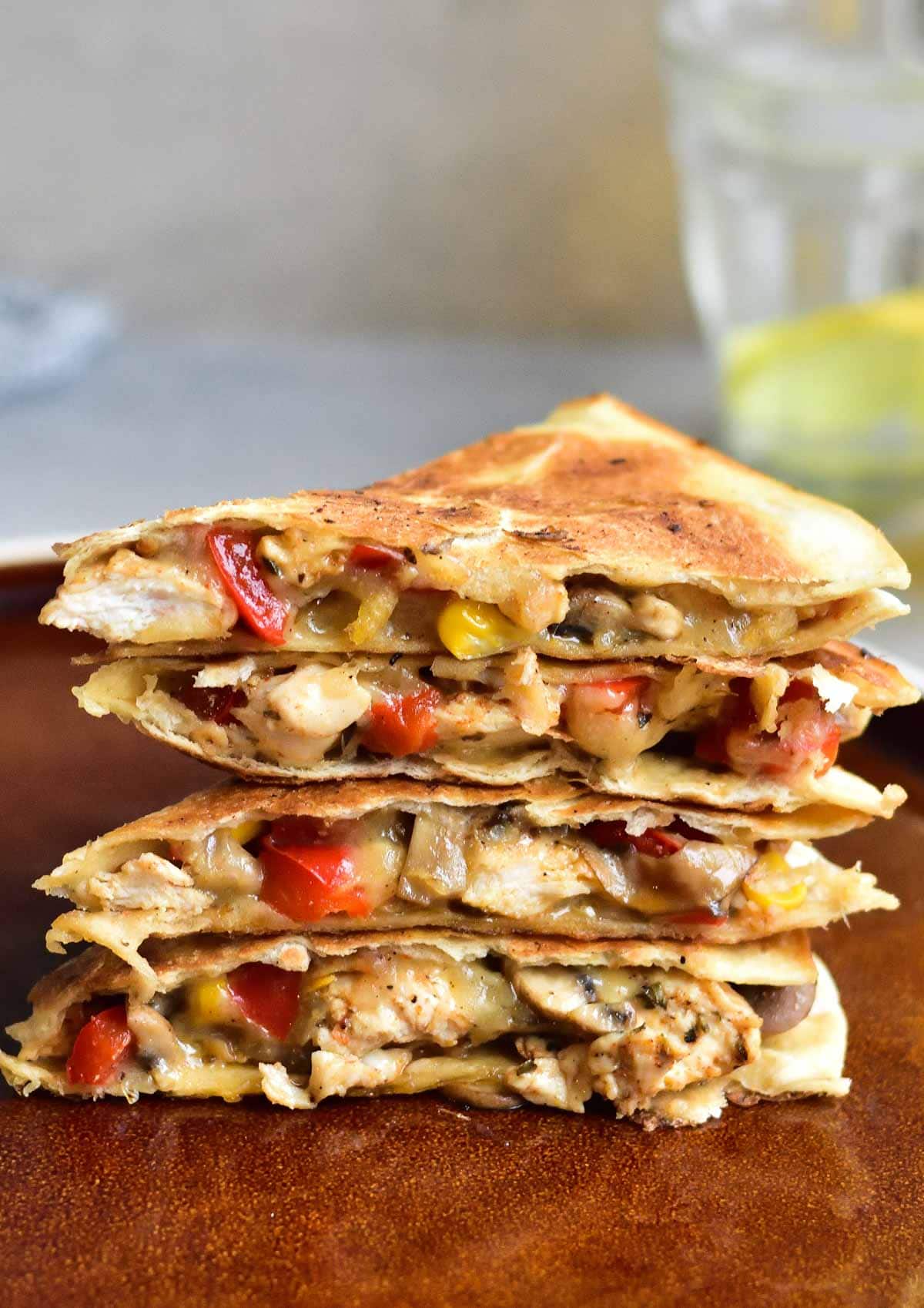 A stack of chicken quesadillas on a brown plate.