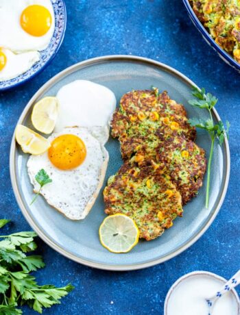 zucchini and corn fritters with fried egg on a blue plaze