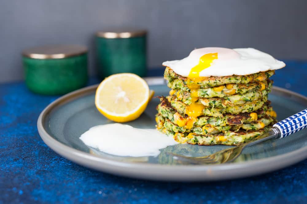 a stack of zucchini corn frittes with poached egg and yogurt