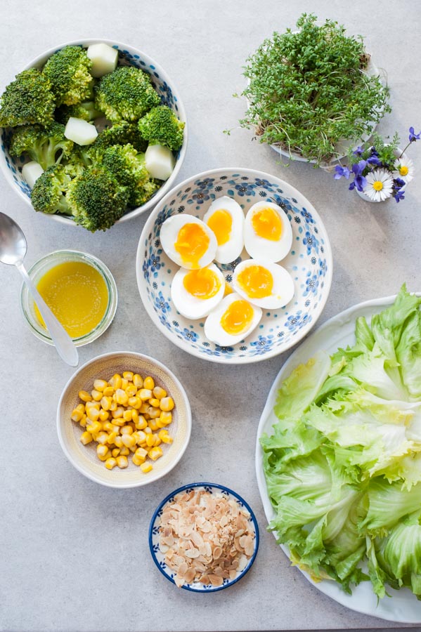Składniki na sałatkę z brokułem i jajkiem, kukurydzą oraz sosem musztardowo-miodowym na stole