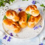 easter bunny rolls on a white plate, flowers in the background