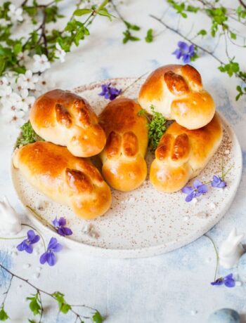 easter bunny rolls on a white plate, flowers in the background