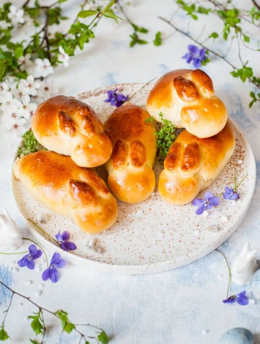 easter bunny rolls on a white plate, flowers in the background