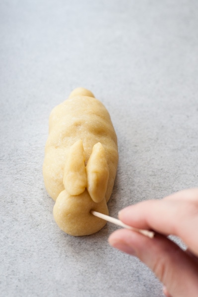 A hole is being procked with a toothpick in a raw yeast dough