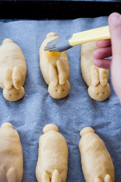 Easter bunny rolls are being brushed with beaten-egg mixture
