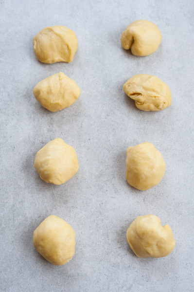 8 yeast dough balls on a baking paper lined baking sheet