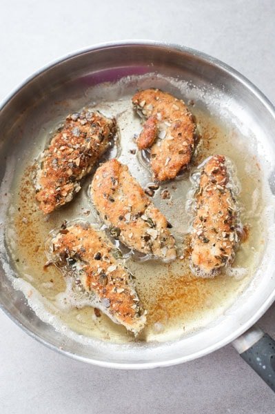 Breaded chicken tenderloins are being pan-fried on a frying pan