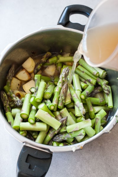 asparagus in a pot, broth is being poured in the pot