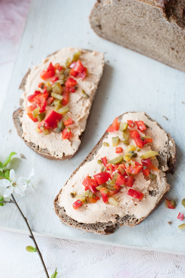 liptauer spread on a piece of bread, sprinkled with bell pepper, gherkins and capers relish