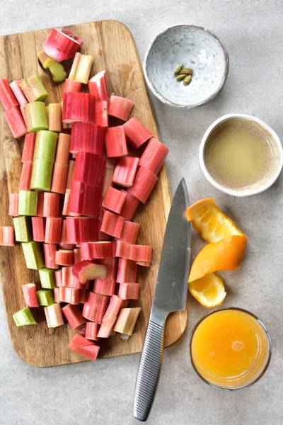 Sliced rhubarb on a chopping board, lemon and orange juice