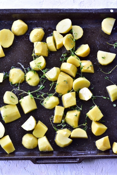 Potatoes and thyme on a baking tray