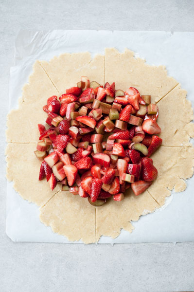 rhubarb and strawberries pilled up in the center of a rolled-out shortcrust pastry dough