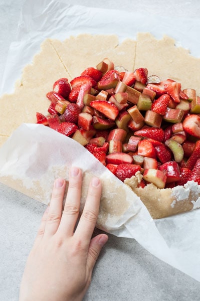 shortcrust pastry is being folded over strawberries and rhubarb