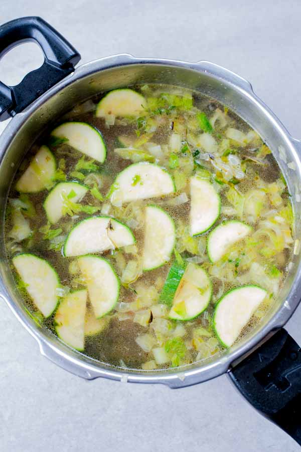 browned vegetables covered with water in a pot