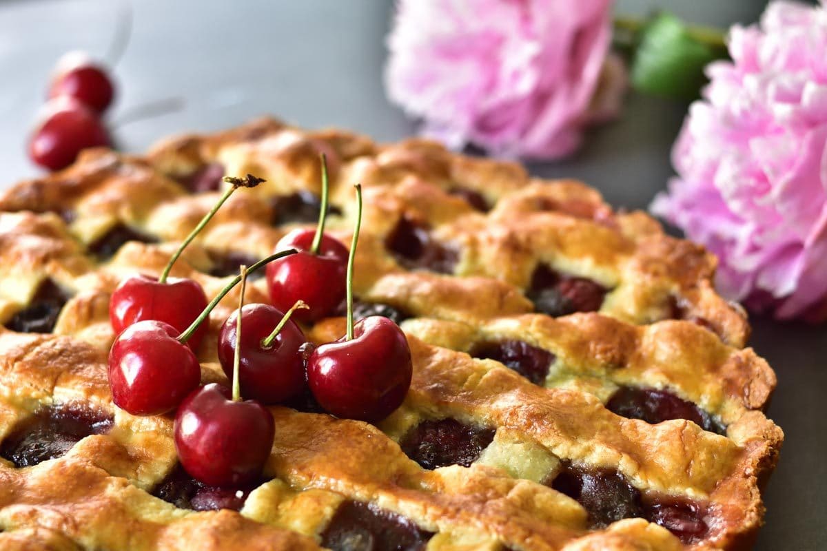 close up picture of a cherry tart topped with fresh sweet cherries
