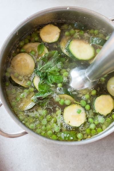 zucchini soup is being pureed with an immersion blender