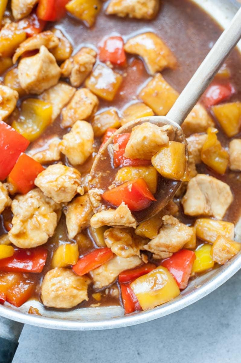 Close up picture of sweet and sour chicken with pineapple and bell paprika in a pan.
