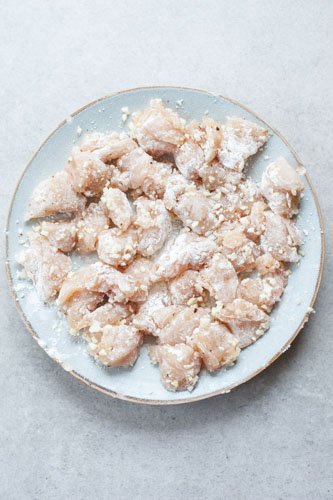 chicken breast pieces tosses in potato starch on a plate