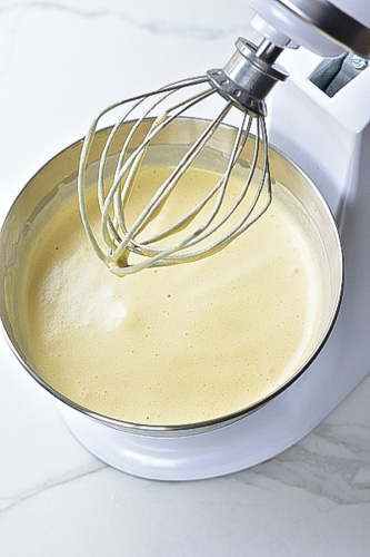 fluffy and pale whisked eggs and sugar in a metal bowl