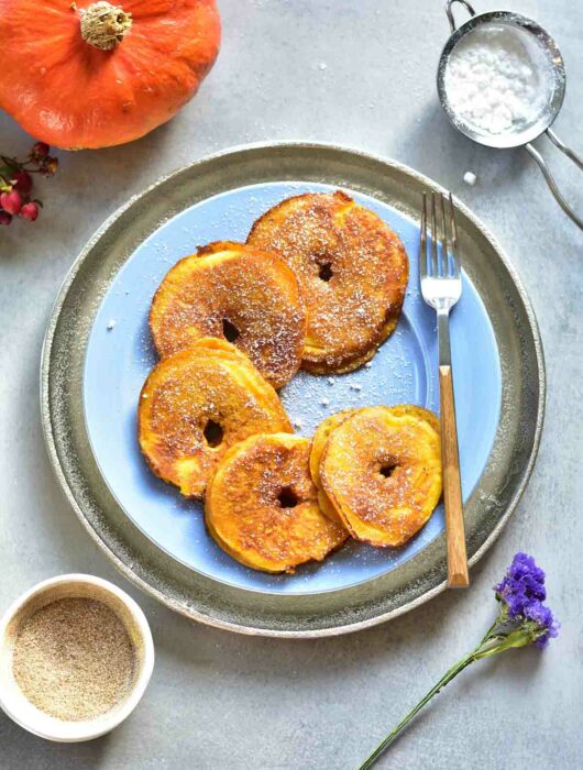Pumpkin apple ring pancakes on a blue plate.