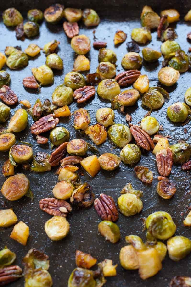 roasted brussel sprouts with pineapple and pecans on a baking tray