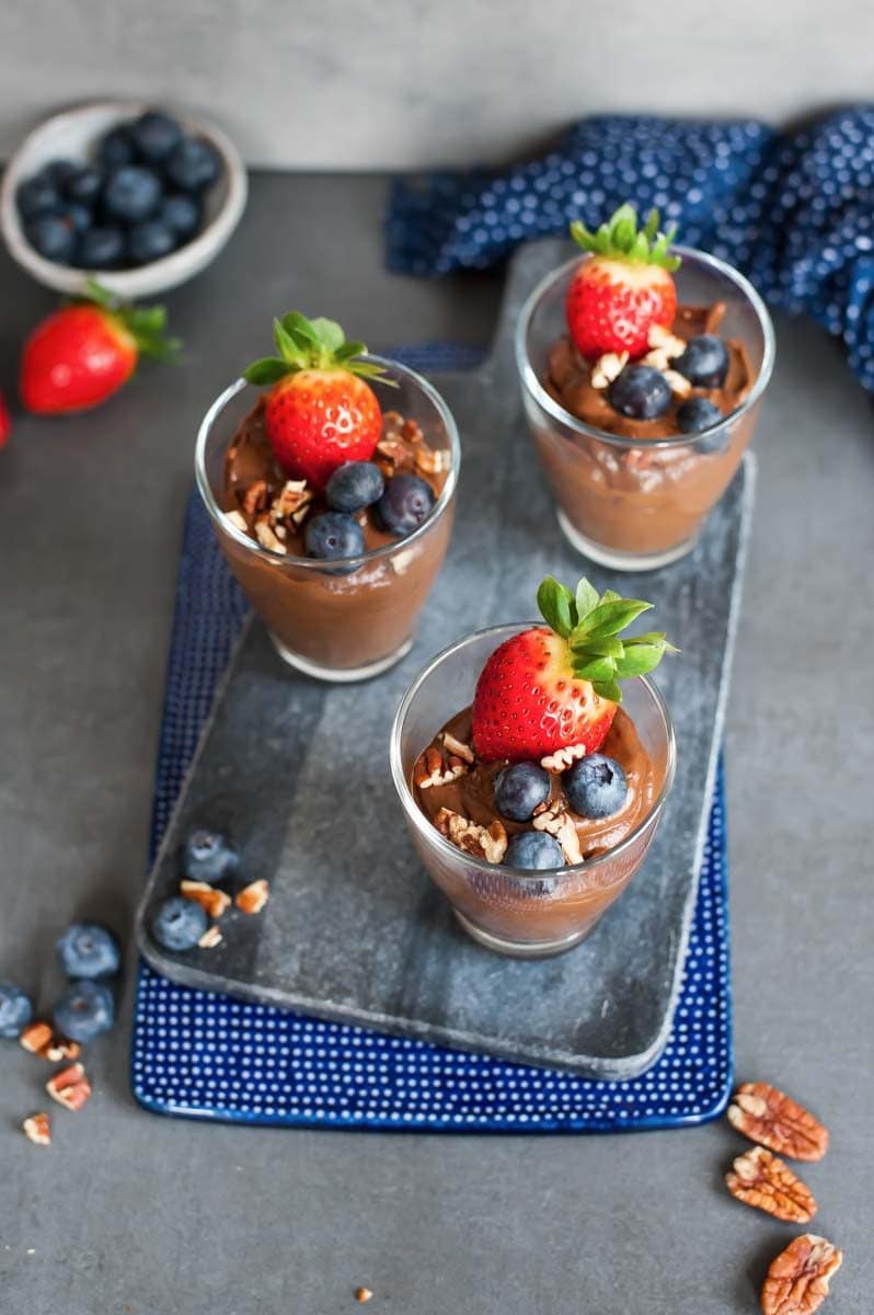 Healthy chocolate pudding in 3 glasses, topped with berries.