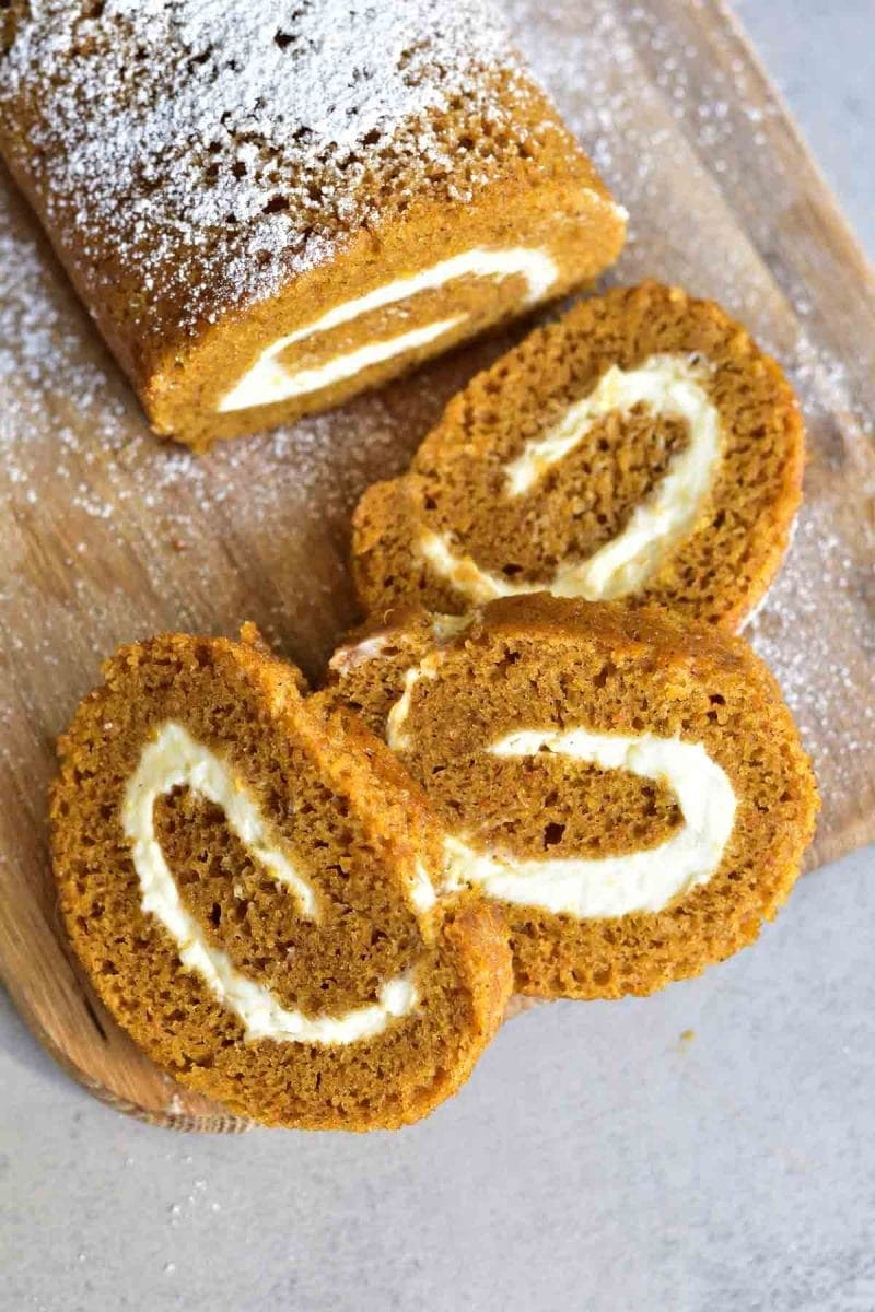 pumpkin roll with orange cream cheese, pumpkin roll slices on a wooden board