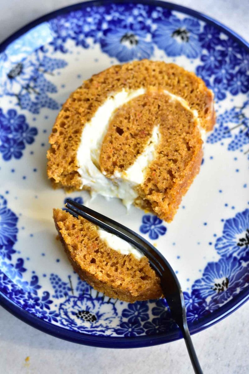 A slice of pumpkin roll on a blue floral plate.
