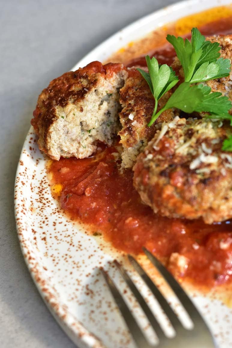 close up shot on ricotta meatballs cut in half on a white plate