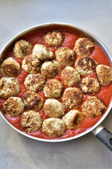 ricotta meatballs are being simmer in tomato sauce
