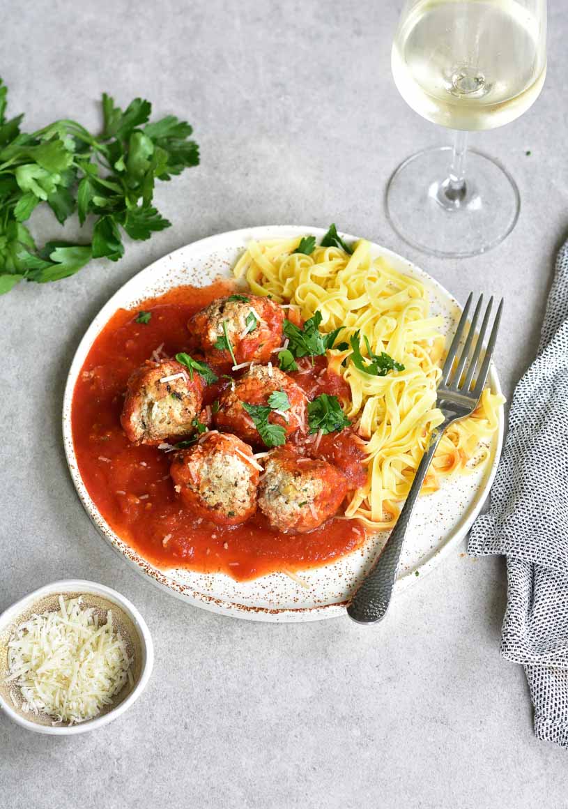 ricotta meatballs with spicy tomato sauce and tagliatelle pasta on a white plate