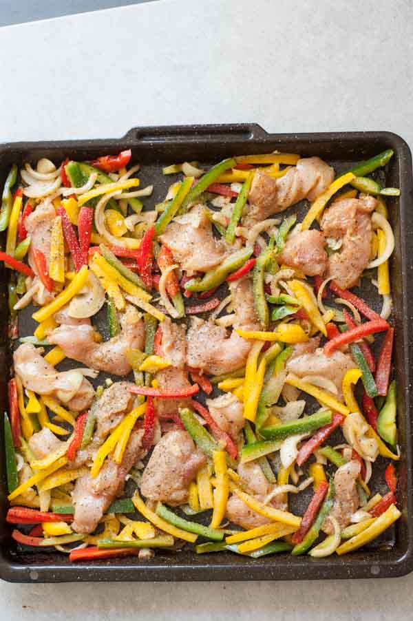 kurczak i warzywa wymieszane z przyprawami na blaszce do pieczenia