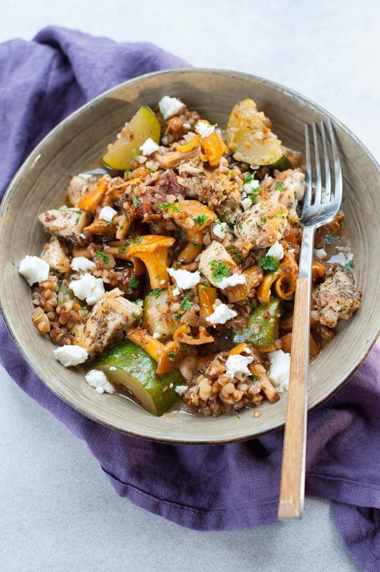 Buckwheat risotto with sun-dried tomatoes, zucchini, and chanterelle mushrooms in a green plate.