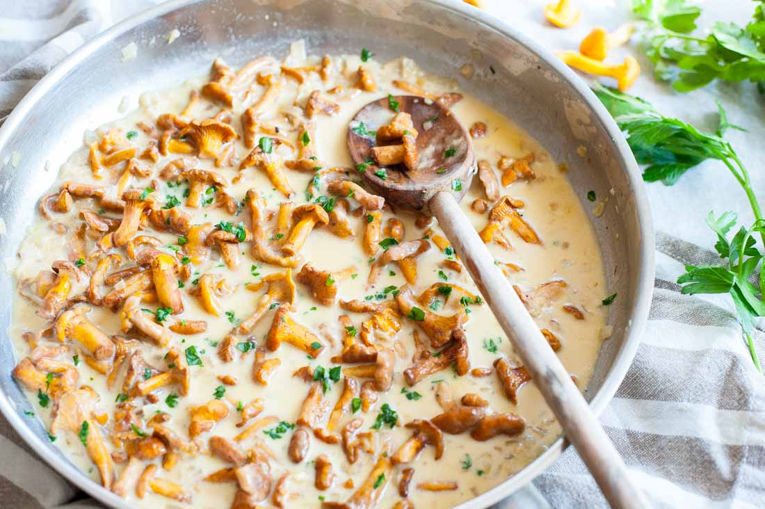 Chanterelle sauce in a pan with a wooden spoon.