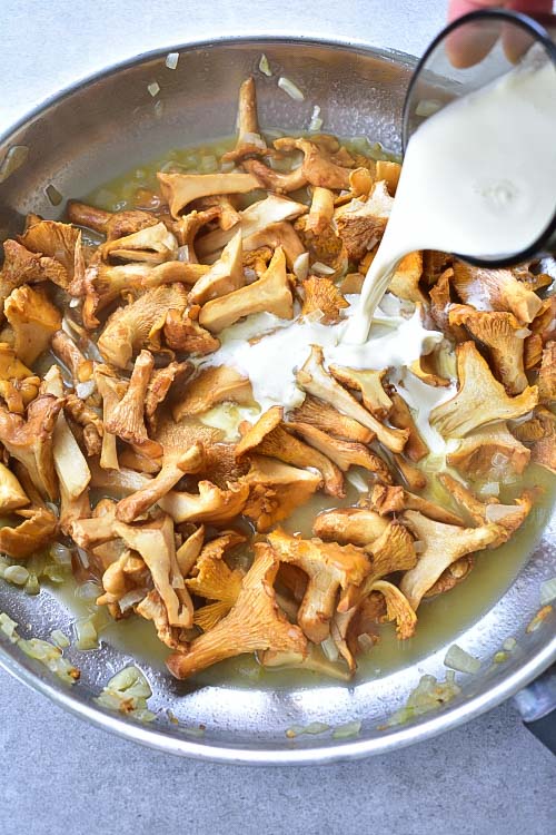 cream is being poured over in a pan with chanterelle mushroom