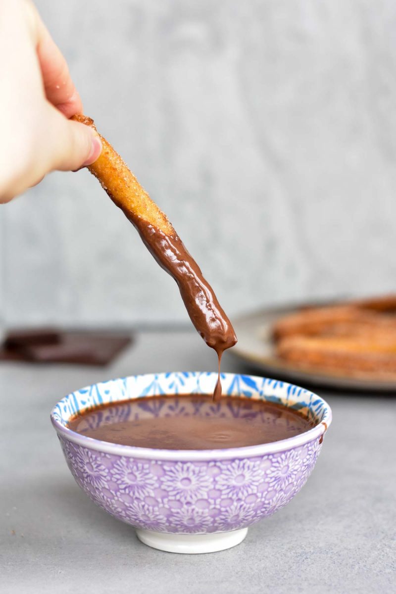Churro is being dipped in chocolate sauce