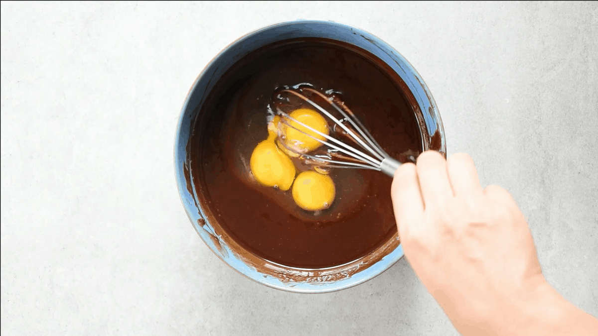 eggs added to melted chocolate in a bowl