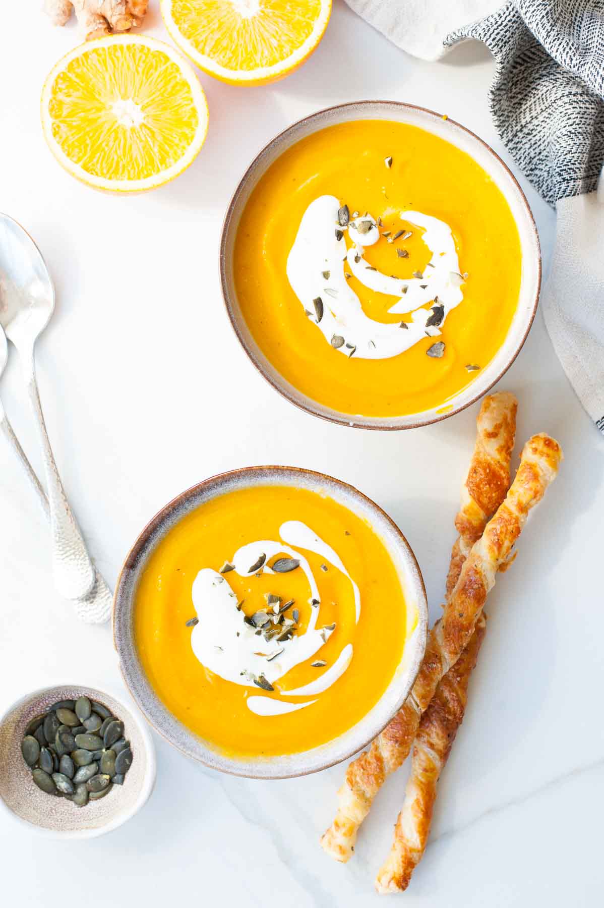 Two bowls with pumpkin and ginger soup with orange.