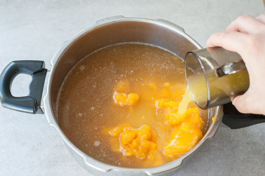 orange juice is being added into a pot