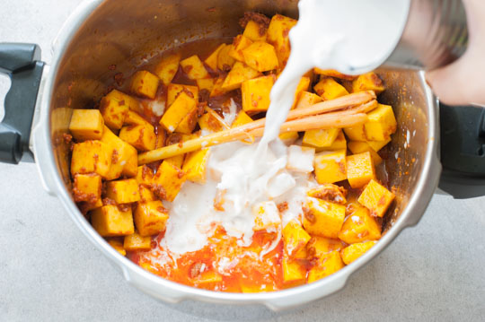 coconut milk is being added to a pot