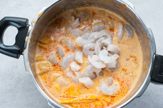 shrimps are being poached in red curry broth