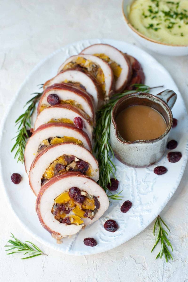 Turkey roulade with butternut squash, mushroom and cranberry stuffing on a white plate.