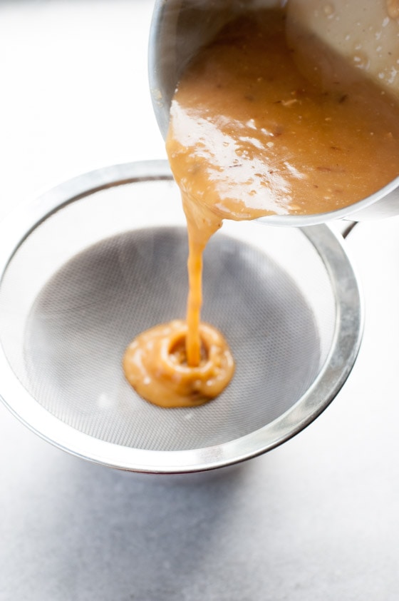 gravy is being strained through a sieve