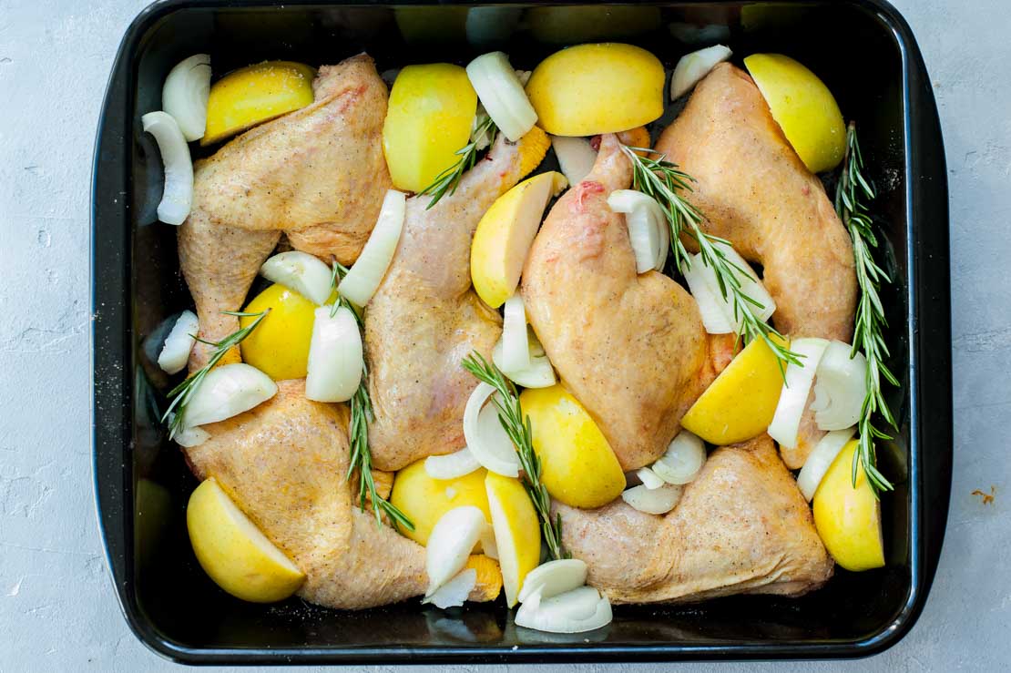 Baked chicken with apples and onions in a baking dish ready to be baked