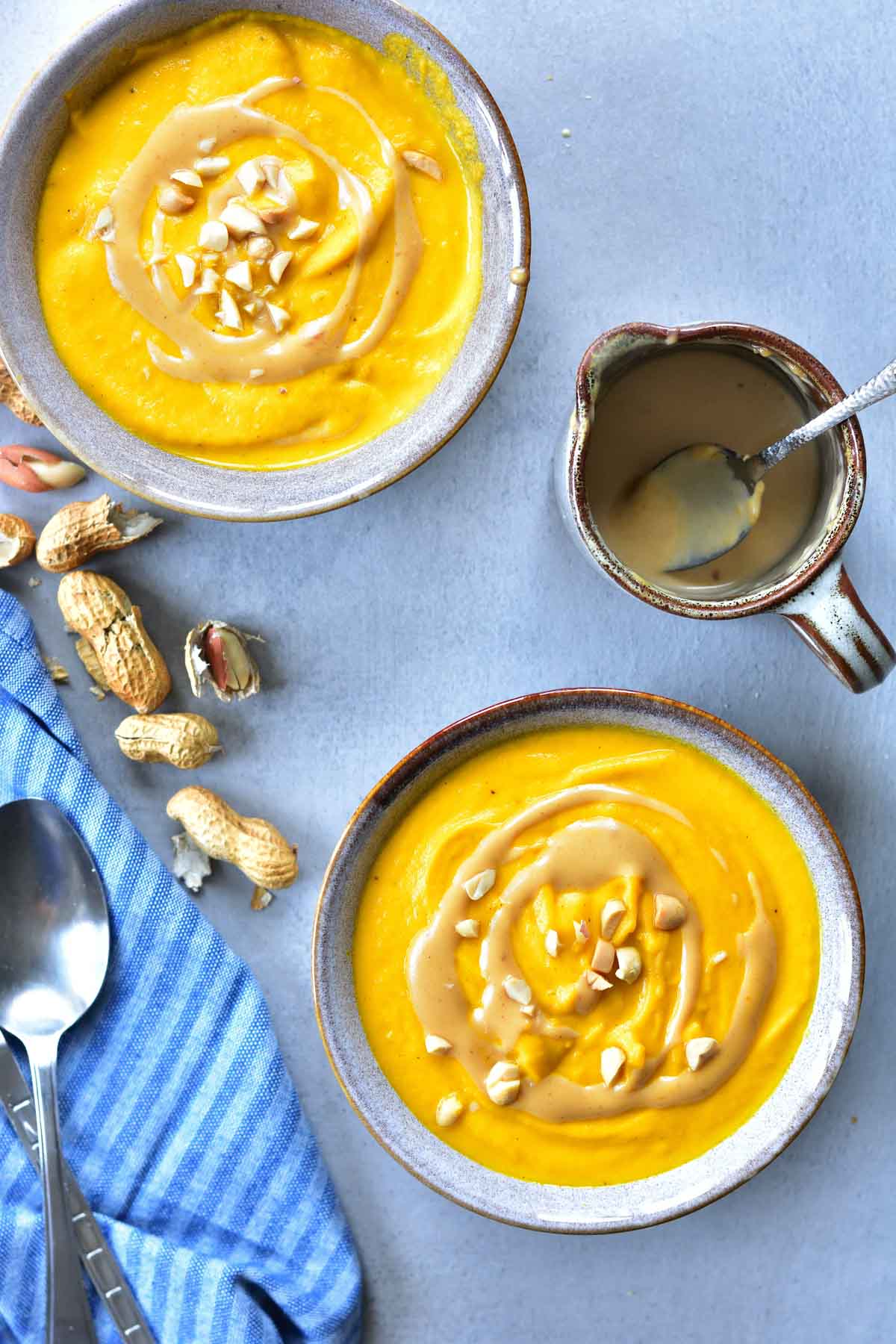 Carrot coconut soup with peanut butter sauce in two bowls
