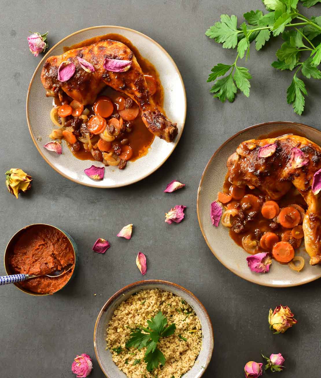 two plates with Harissa chicken with rose water sauce, a bowl with lemon couscous