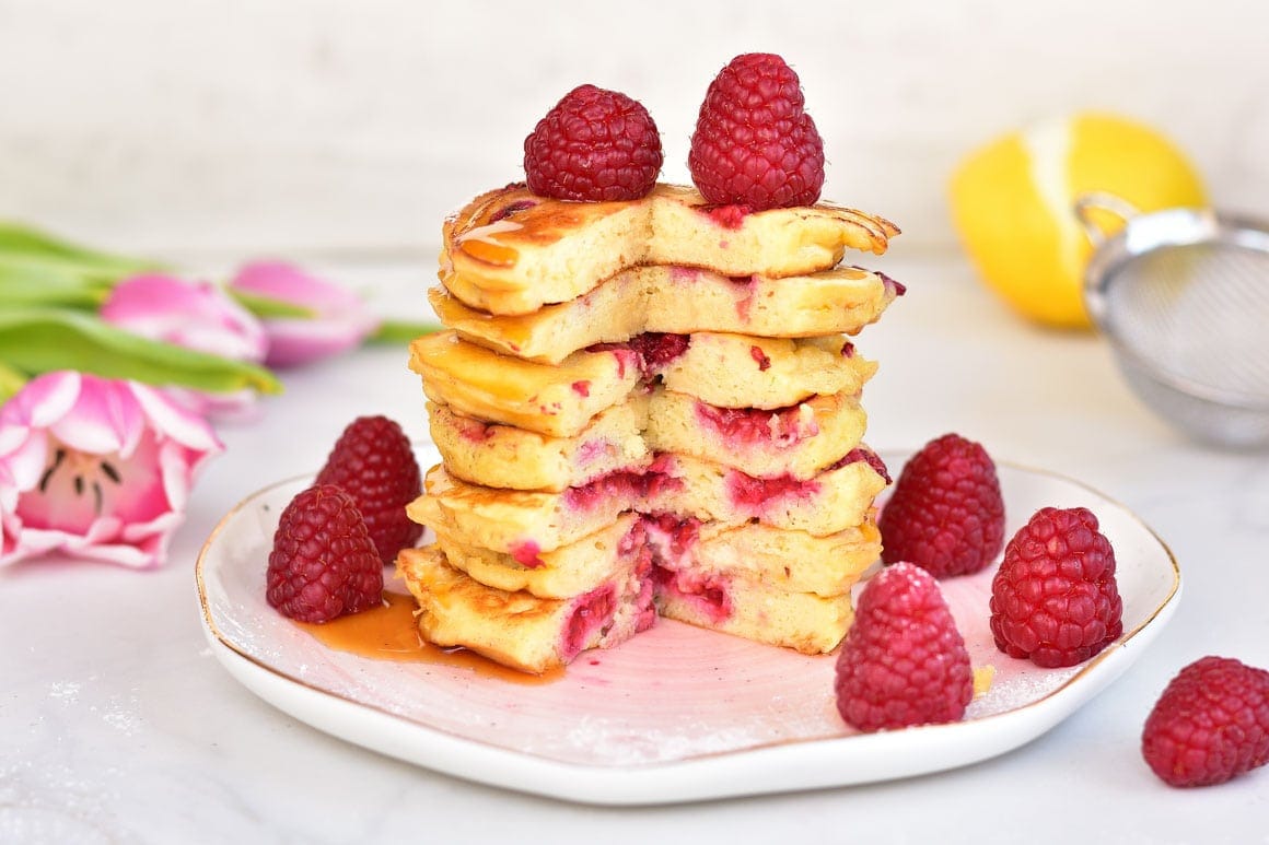 A stack of lemon ricotta pancakes on a rose plate.