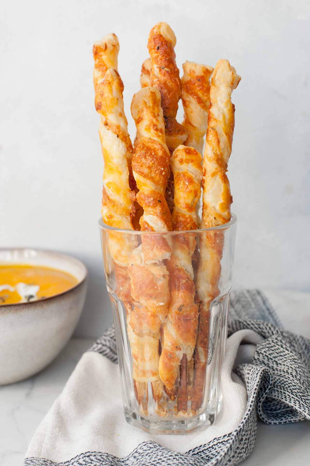 Puff pastry cheese straws in a glass.