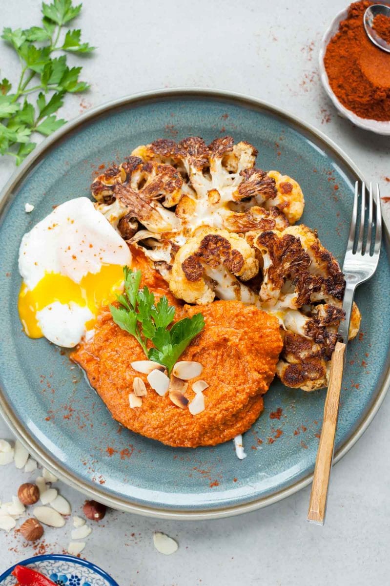 roasted cauliflower steaks with romesco sauce and a poached egg on a blue plate
